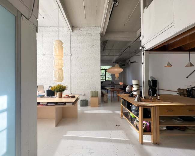 The image shows a spacious interior featuring a modern open-concept layout with a wooden kitchen island, a dining area, and large windows allowing natural light to fill the room.