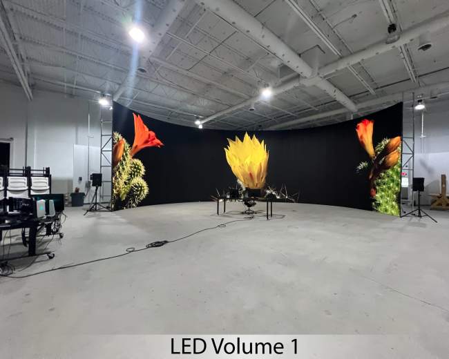 The image shows a spacious studio with a curved LED screen displaying vibrant flower graphics, surrounded by audio equipment and lighting stands.
