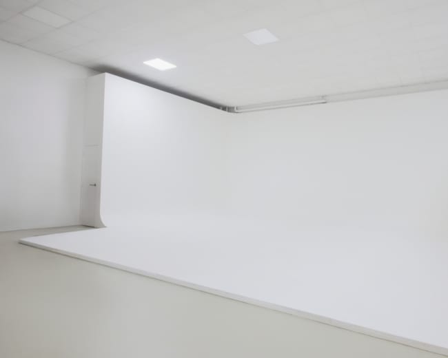The image shows a spacious white studio with a seamless backdrop and plain flooring.