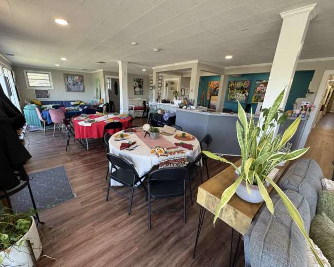 The image shows a spacious interior with multiple tables set for dining, colorful decor on the walls, and various seating arrangements.