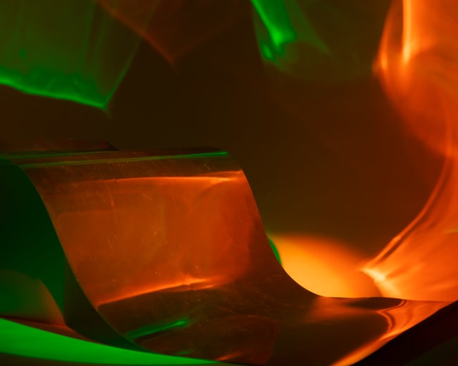 The image features colorful light projections creating abstract patterns on a surface.