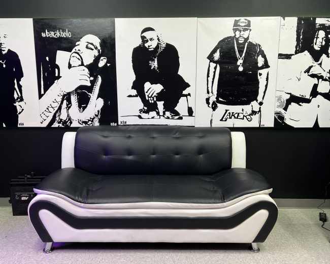 A black and white couch in front of a wall featuring large black and white portraits of men.