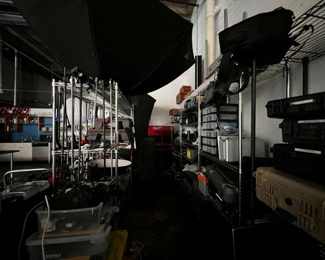 A dimly lit storage area with metal shelves lined with various equipment cases and tools.
