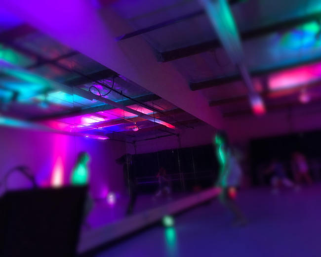 A dance studio with colorful lighting and dancers in motion.