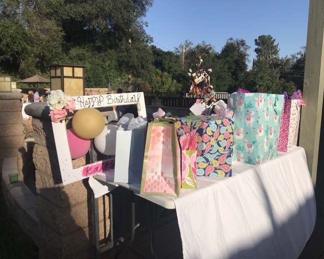 A table is decorated with a variety of wrapped birthday gifts and a sign that reads "Happy Birthday."