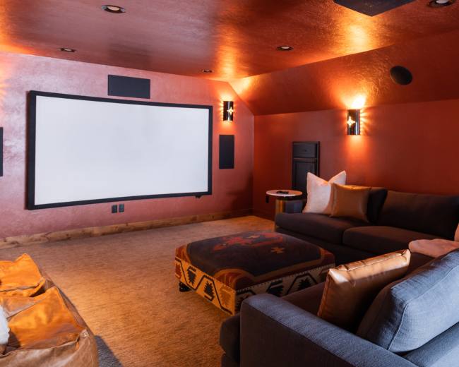 A cozy home theater room with a large projection screen, comfortable seating, and warm lighting.