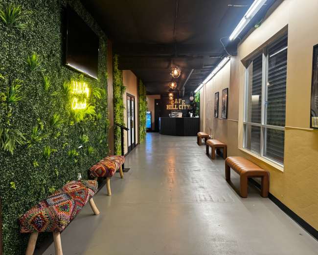 The image shows a hallway with green wall decor, wooden benches, and a reception area at the end.