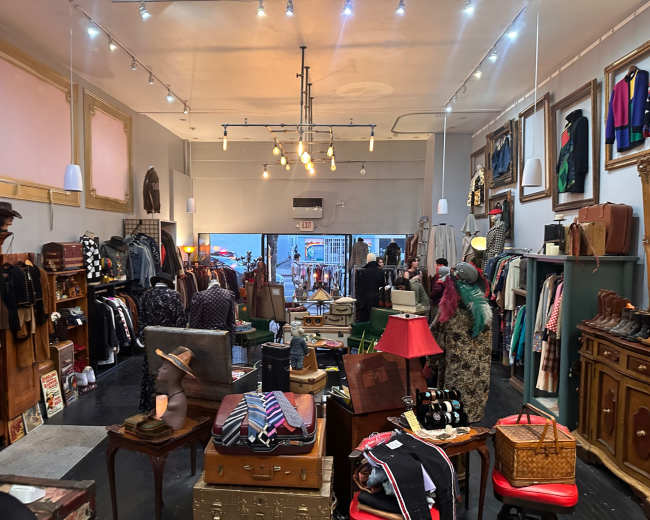 A well-organized vintage clothing store showcases a variety of apparel, accessories, and decor arranged on racks and displays.