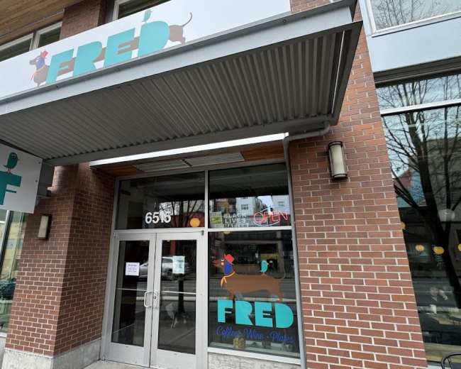The image shows the exterior of a café called "FRED," featuring a brick façade and large windows with colorful signage.