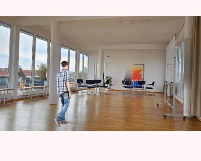 A person walks across a spacious, modern conference room with large windows and minimal furniture.