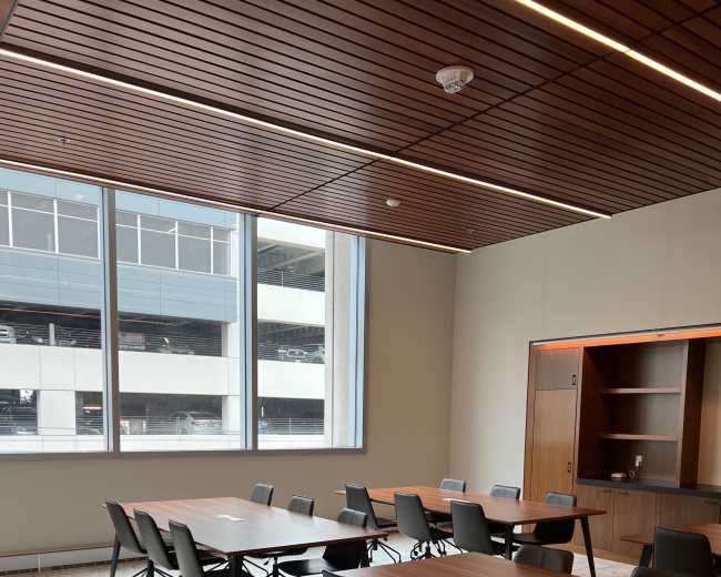 The image shows a modern conference room with multiple tables arranged in a U-shape and large windows providing natural light.