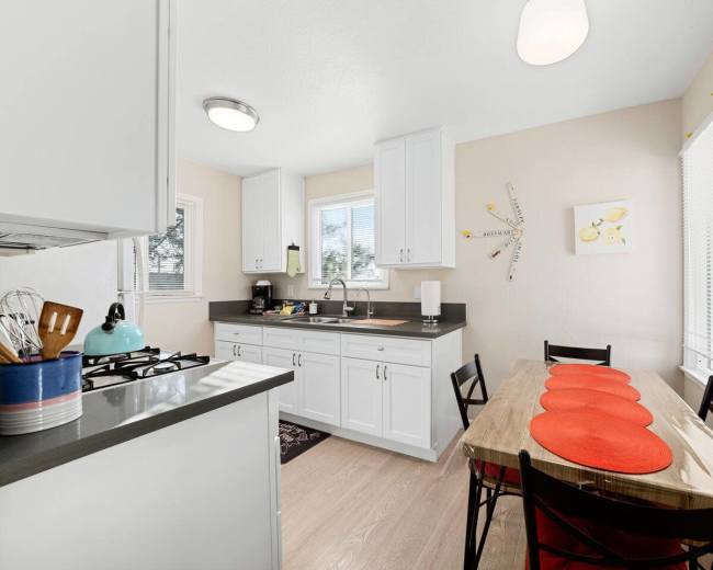 The kitchen features white cabinetry, a gray countertop, and a small dining table with red placemats.