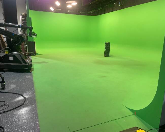 The image shows an empty green screen studio with a single cart positioned in the center.