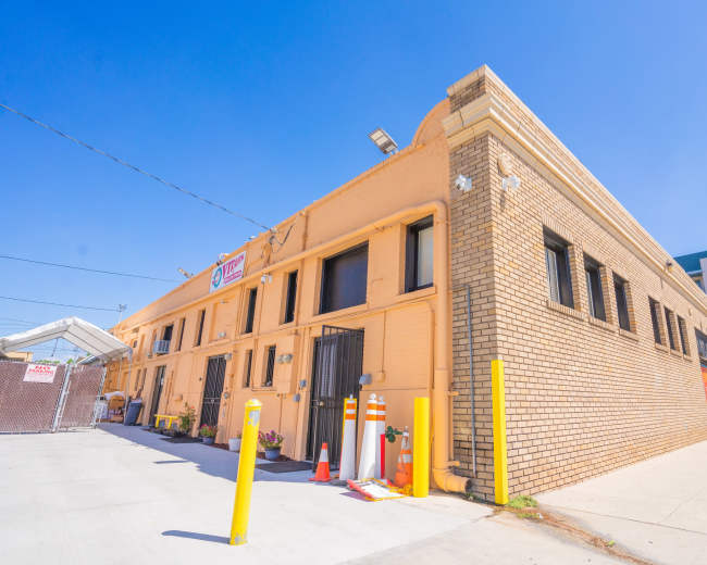 A yellow brick building with multiple windows, located in an urban area with a clear blue sky.