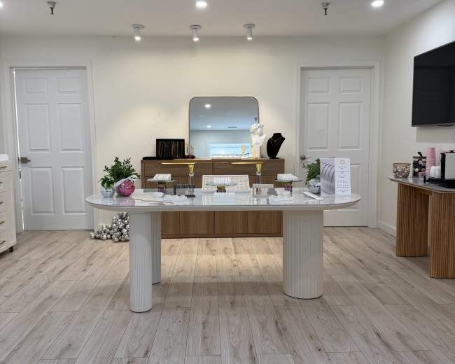 The image shows a neatly organized retail space with a central display table and two white doors in the background.