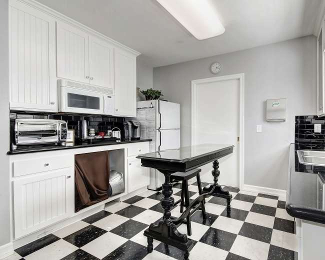 The kitchen features black and white checkered flooring, white cabinetry, and a central island with a black countertop.