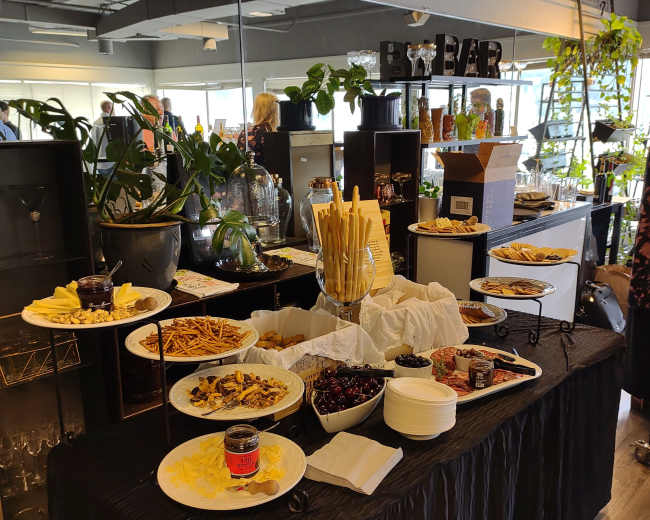 A buffet table is set with various appetizers and snacks, surrounded by indoor plants and decorative items.