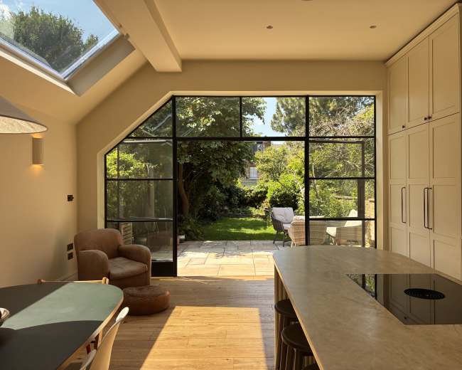 The image shows a modern kitchen with a large glass door leading to a lush garden area.