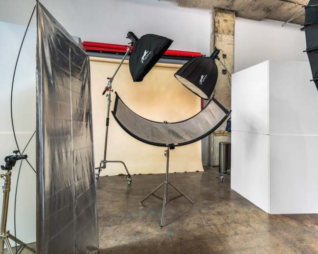 A photography studio setup with softbox lights, a curved reflector, and large white panels.