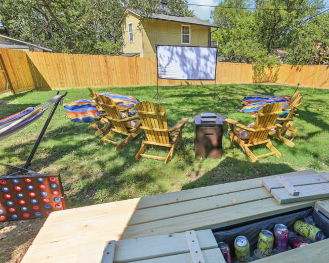 The image features a backyard setup with a projection screen, several wooden chairs arranged in a circle, and two hammocks nearby.