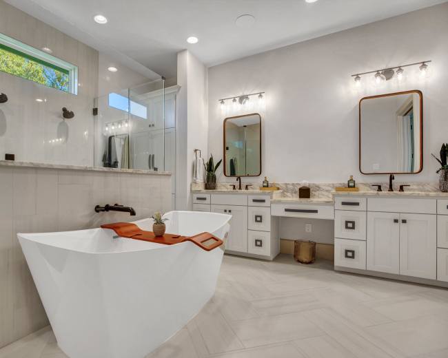 A modern bathroom featuring a freestanding bathtub, dual sink vanity with mirrors, and a separate glass-enclosed shower.