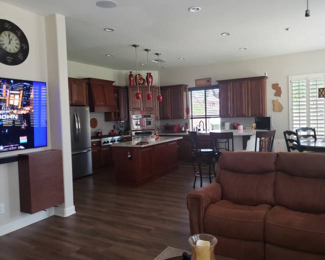 A modern kitchen and living area featuring dark wooden cabinetry, stainless steel appliances, and a seating area with a brown couch.