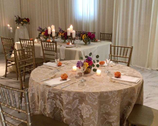 Elegantly set dining tables with floral centerpieces and candles in a softly lit room.