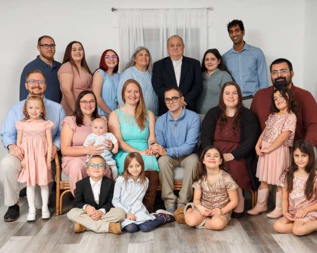 A large family group poses together in a bright indoor setting for a photograph.