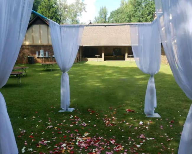 A grassy area is framed by sheer white drapes, with scattered flower petals on the ground.
