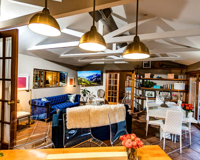 A well-lit, open-concept living and dining area features modern furniture, including a blue sofa, a glass dining table, and a stylish decor arrangement.
