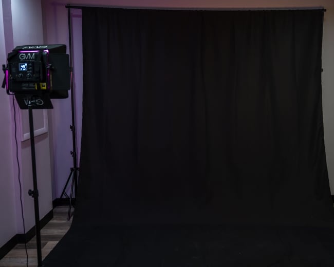 A photography studio with a black backdrop and two lighting fixtures positioned on either side.