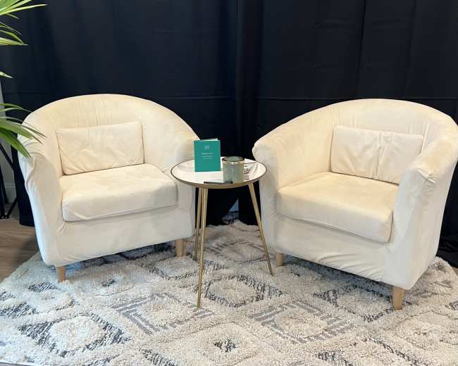 Two cream-colored chairs with round backs are positioned across from each other, accompanied by a small round table on a geometric-patterned rug.