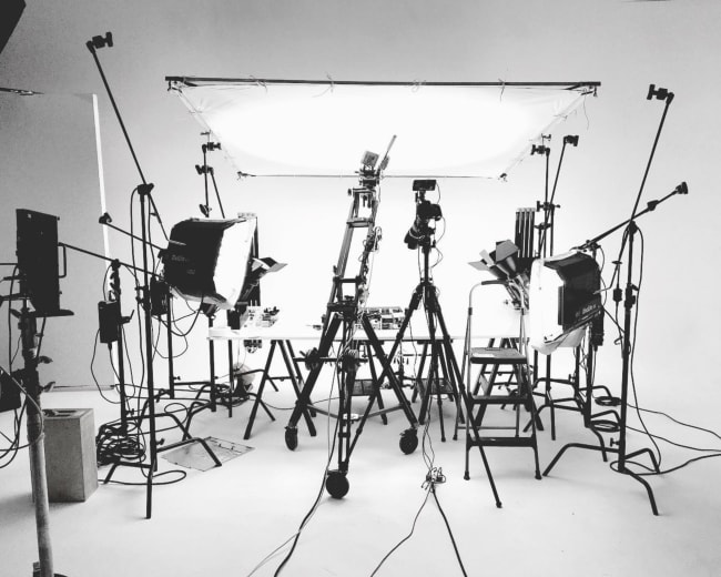 A photography studio setup with multiple lights, tripods, and a white backdrop.