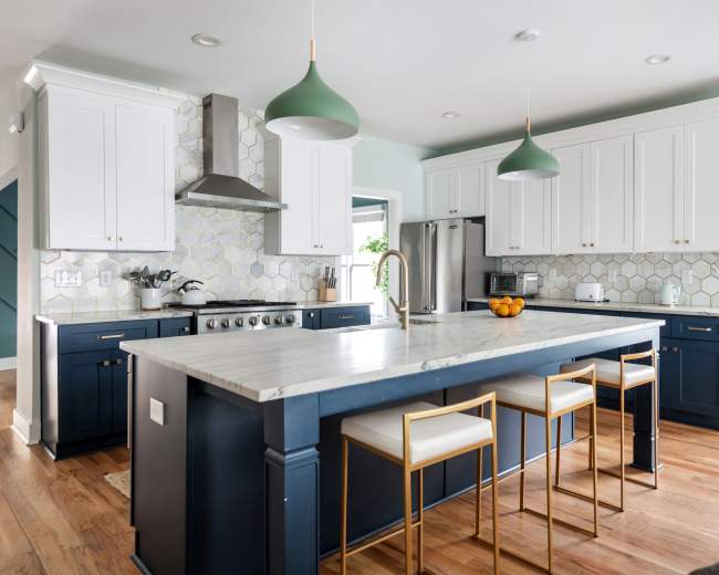 The kitchen features a central island with bar seating, blue cabinetry, white upper cabinets, and a marble countertop.