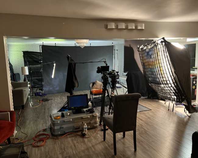 A film setup showcases a camera, lighting equipment, and a backdrop in a spacious living area.