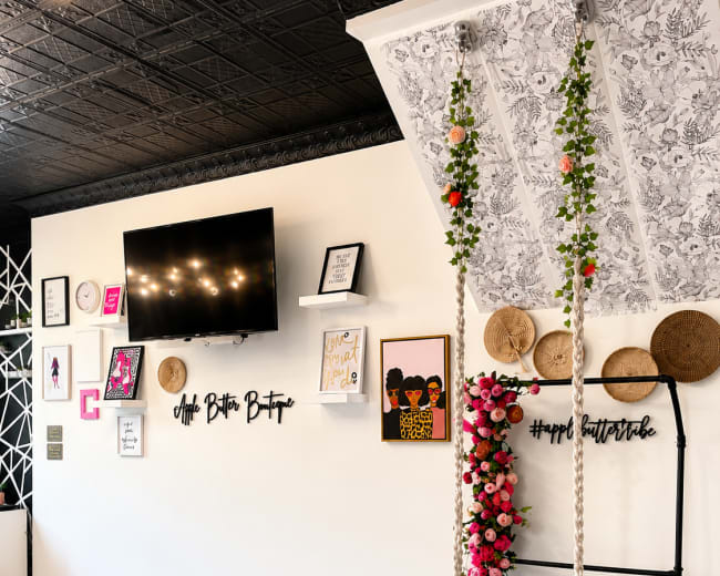 The image shows a stylish interior with a decorative wall featuring a swing adorned with flowers, framed artwork, and a television mounted above.