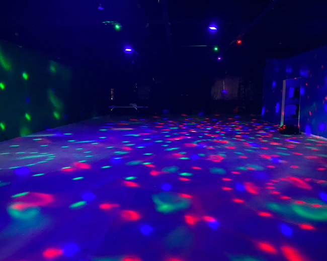 A dimly lit room with colorful lights creating patterns on the floor and walls.