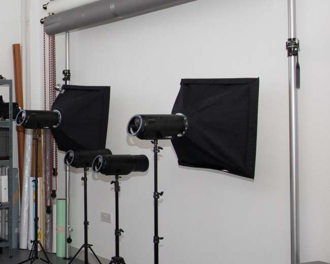 Three lighting setups with softboxes and a wall clock in a photography studio.