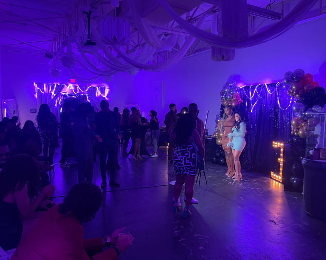 The image shows a vibrant party scene with guests mingling under purple lighting, while a group poses for a photo in front of a decorative backdrop adorned with balloons and lights.