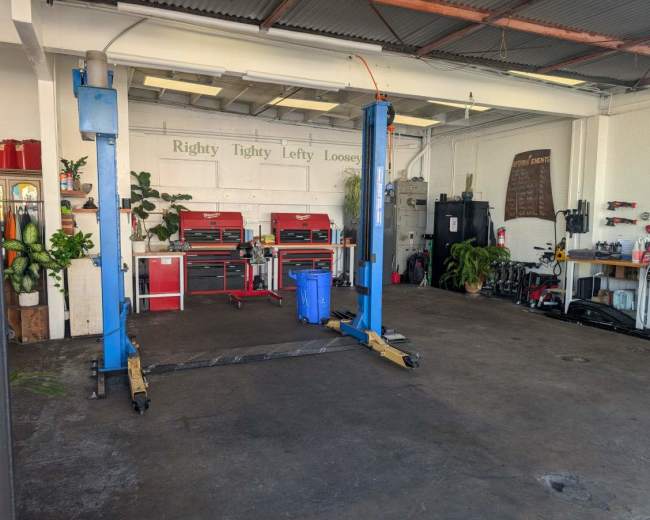 The image shows a garage with blue vehicle lifts, toolboxes, and various automotive equipment along the walls.