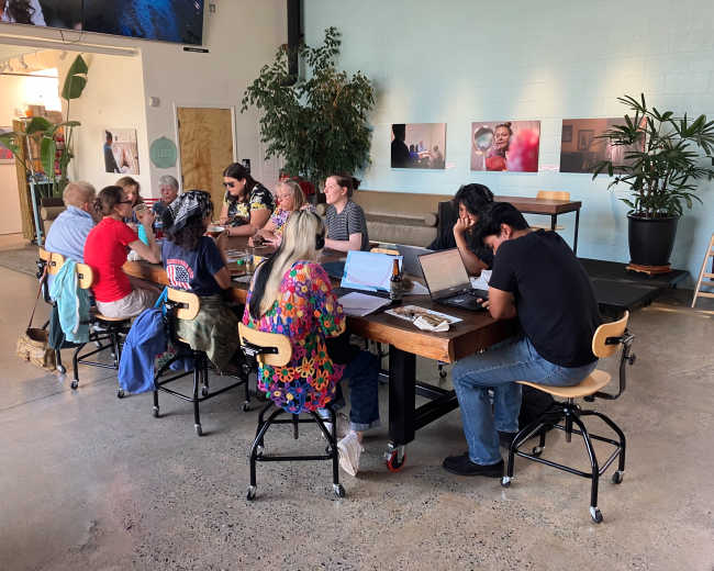 A diverse group of individuals collaborates around a large table in a modern workspace.