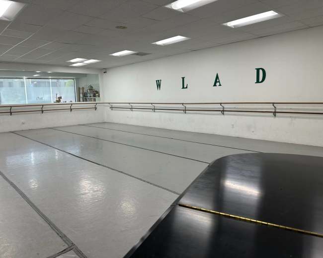 The image shows a spacious dance studio with mirrored walls, a ballet barre, and a black piano in the foreground.