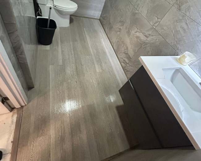 A modern bathroom features a toilet, a sink with a cabinet, and tiled walls and flooring.