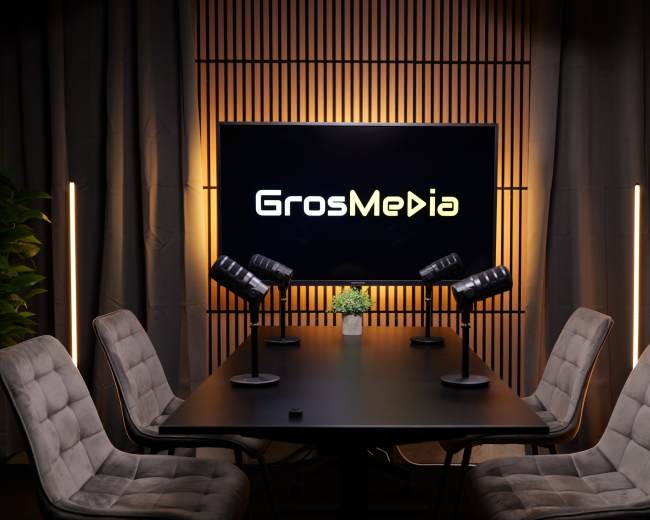 A modern conference room features a large screen displaying "GrosMedia," surrounded by chairs and adjustable lights.