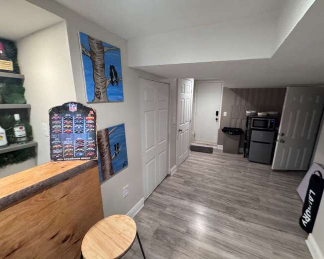 The image shows a well-lit interior space with a small kitchenette, including a mini refrigerator and a microwave, and artwork displayed on the wall.
