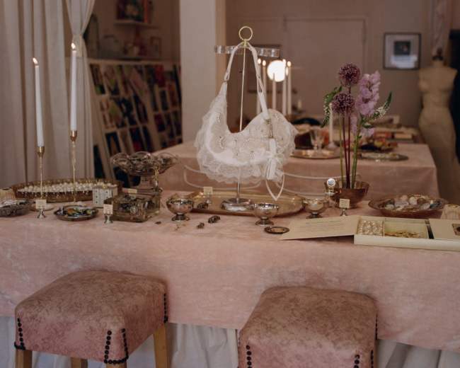 The image shows a well-decorated table featuring various jewelry items, candles, flowers, and elegant decor in a softly lit space.