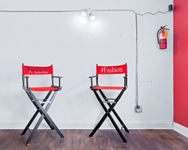 Two red director's chairs with labels, "House of Fashion" and "#Fashion," are positioned against a light gray wall in a minimalist setting.