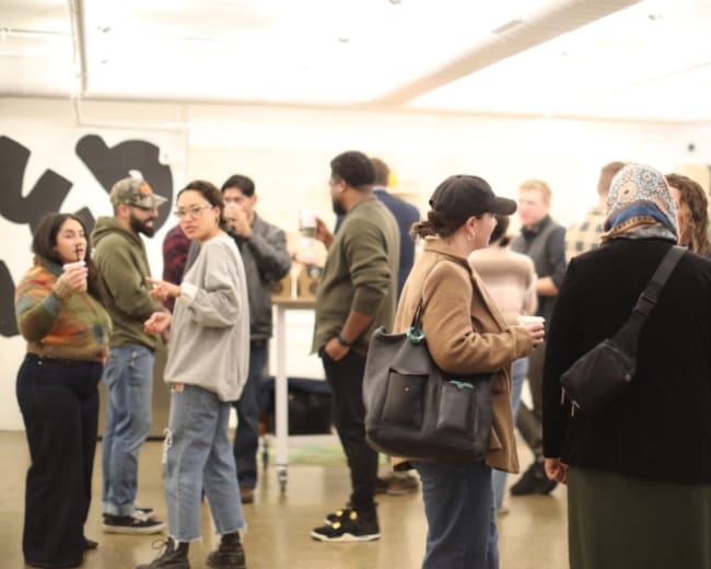 A group of people is socializing in a modern indoor space with tables and a minimalist design.
