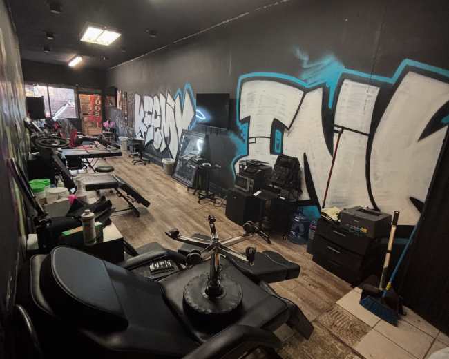 The image shows a gym interior with various exercise equipment lined up against the walls, accented by graffiti-style art on the dark walls.