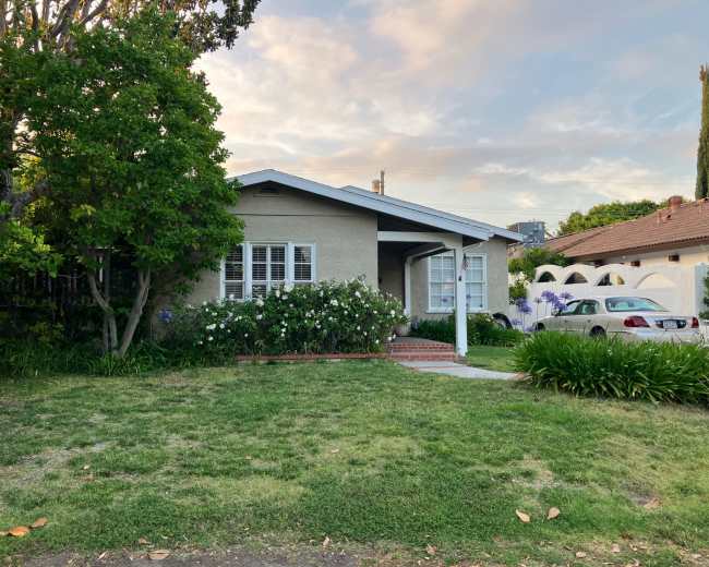 The image shows a single-story house with a landscaped front yard and a parked car in the driveway.